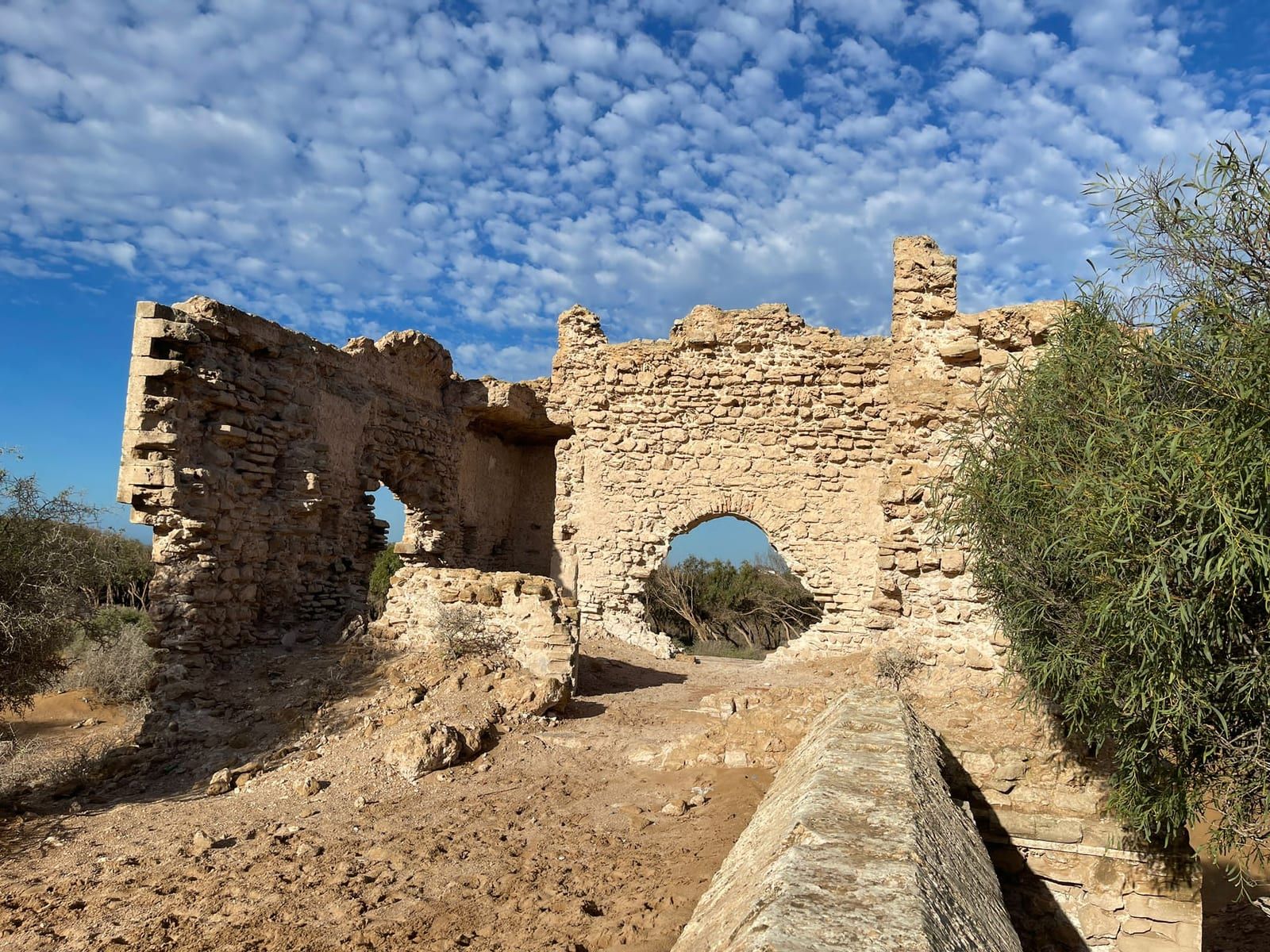 Ruines de pierre à arcades dressées sur un plateau sous un ciel moutonné