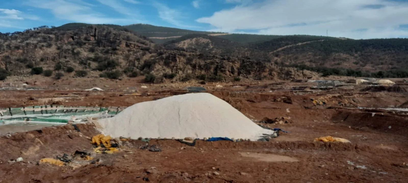 Tas de sel bâché devant les collines boisées