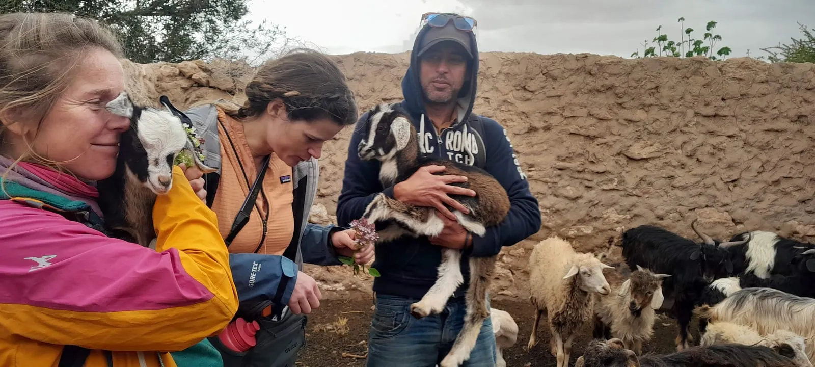 Le berger et deux visiteuses, un chevreau dans les bras, le troupeau à leurs pieds