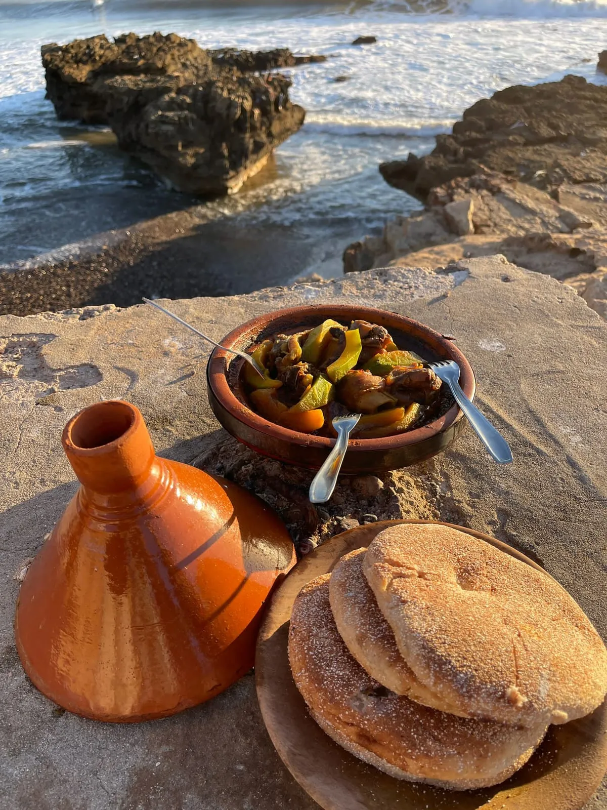 Tajine et pain posés sur la pierre, face à la mer