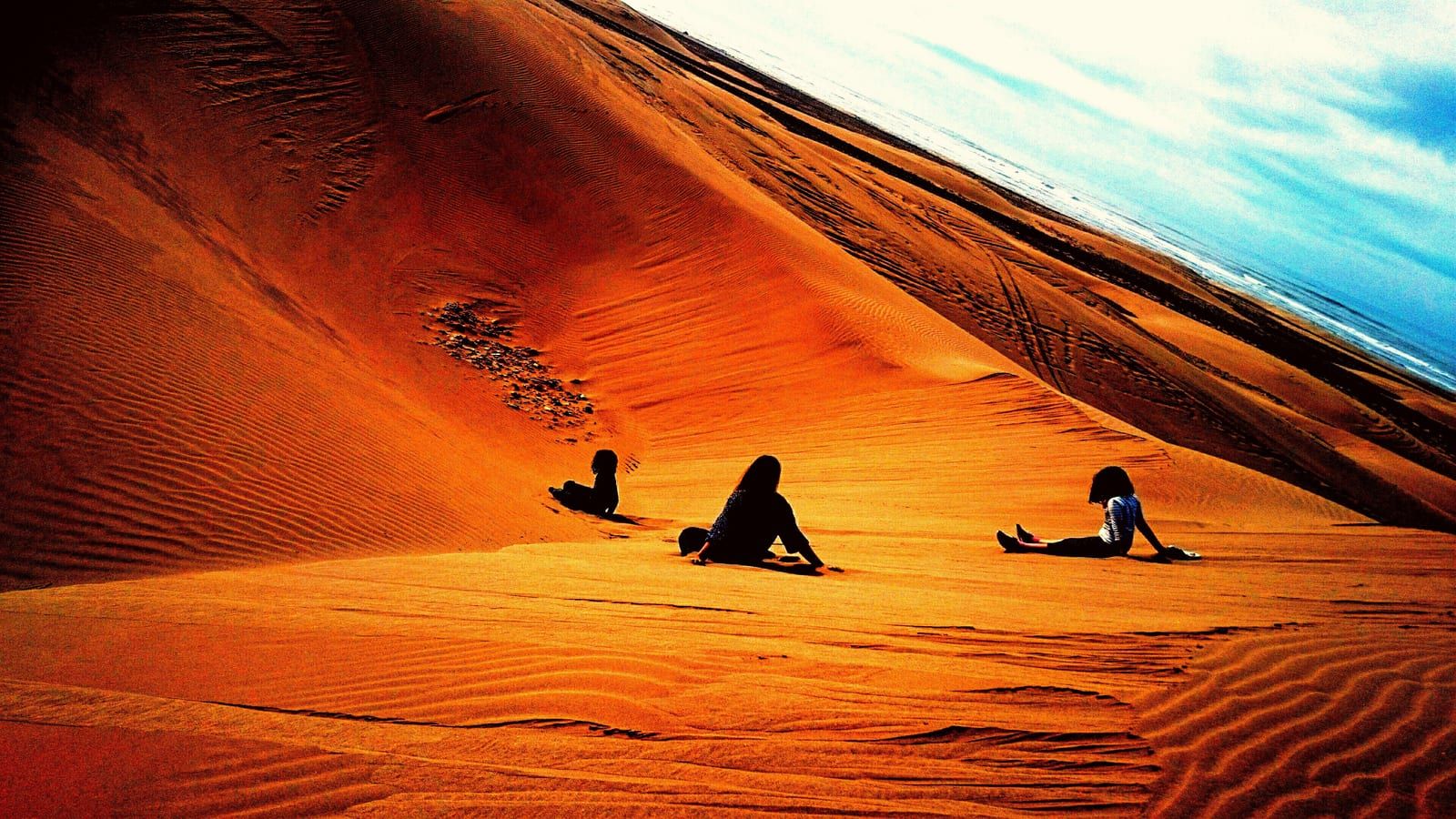 Silhouettes assises sur la grande dune orange