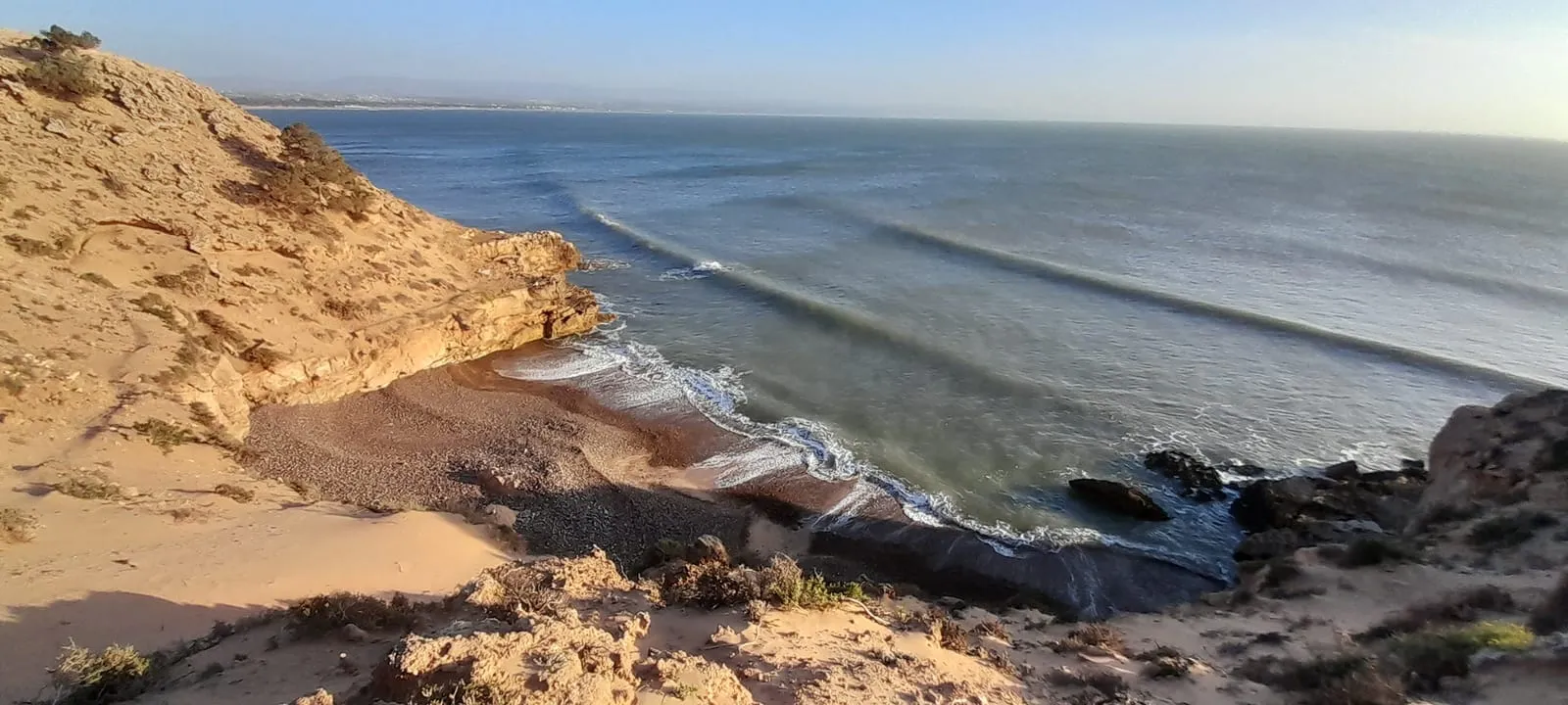Depuis la falaise, la crique et les lignes de houle au soir