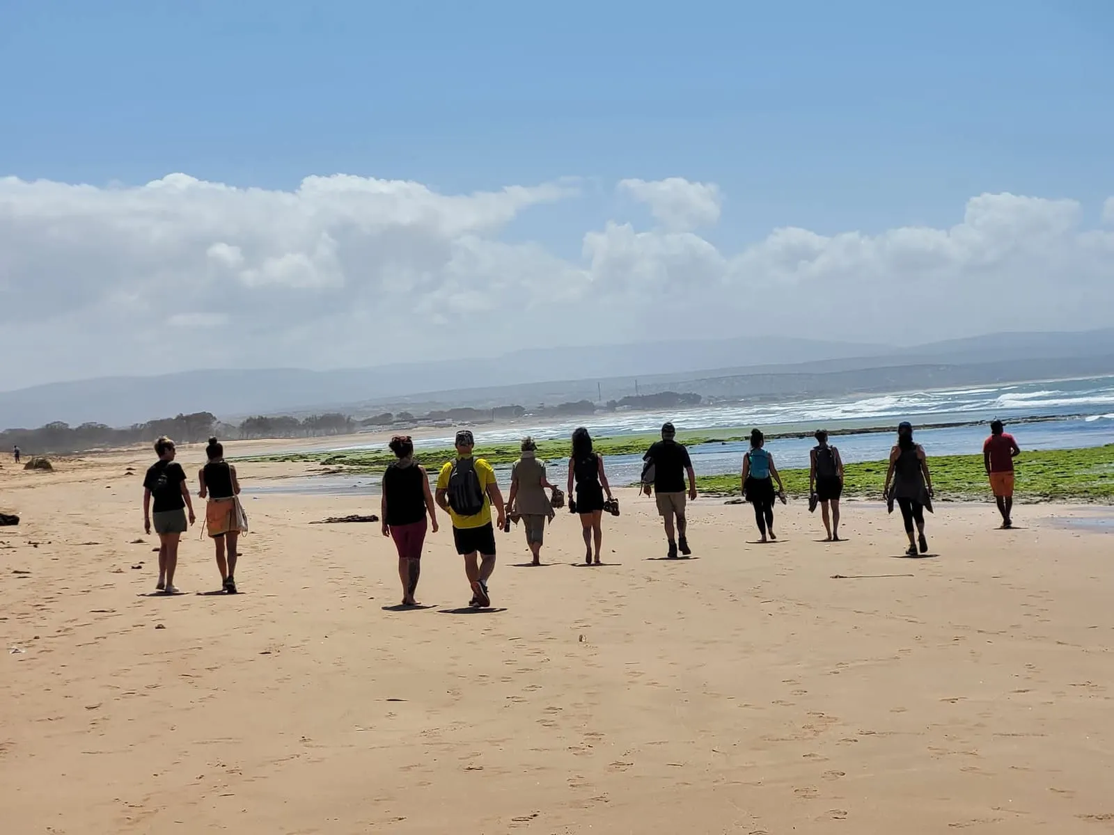 File de randonneurs le long de la plage
