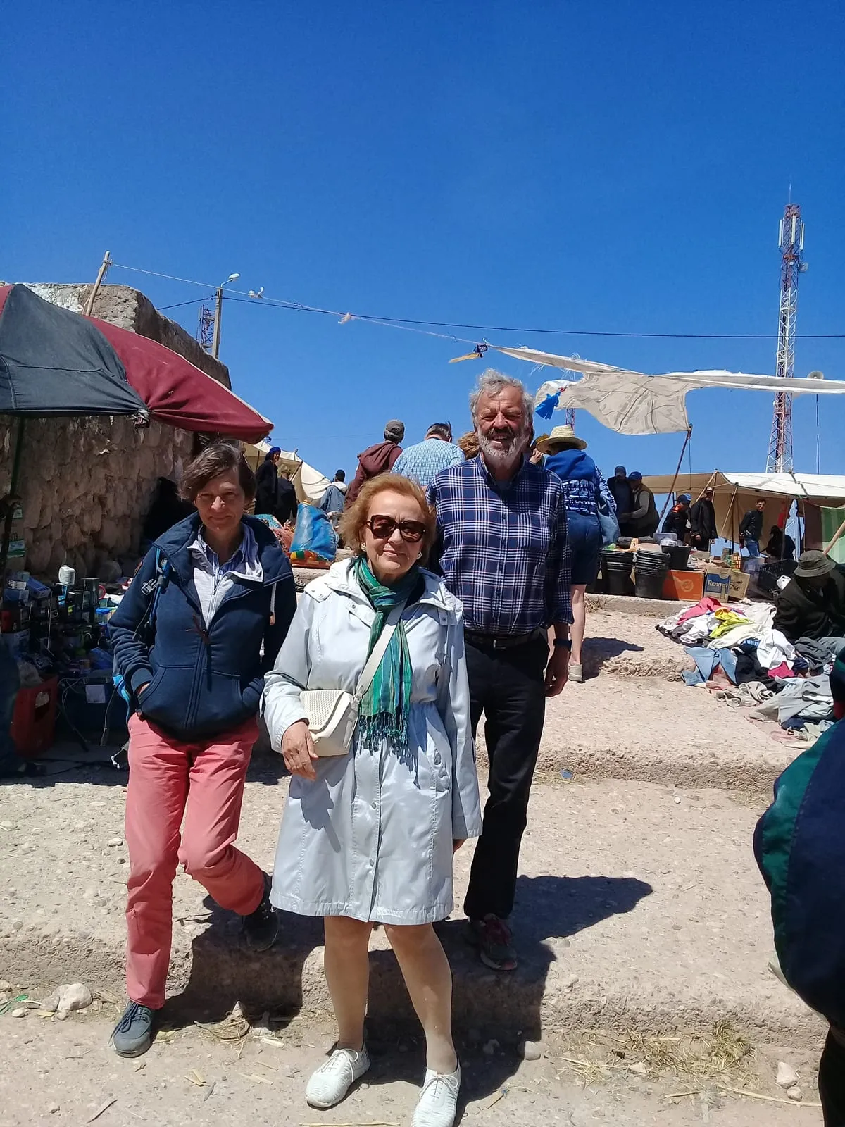 Trois visiteurs dans les allées du souk, les étals et les bâches derrière eux
