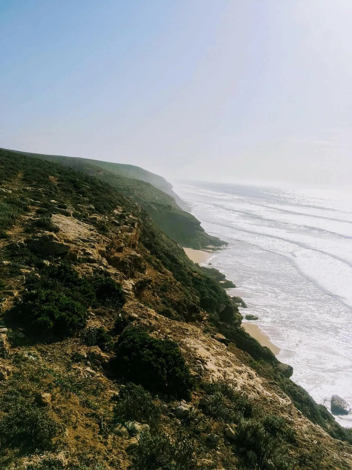 La falaise couverte de broussailles plonge vers la plage