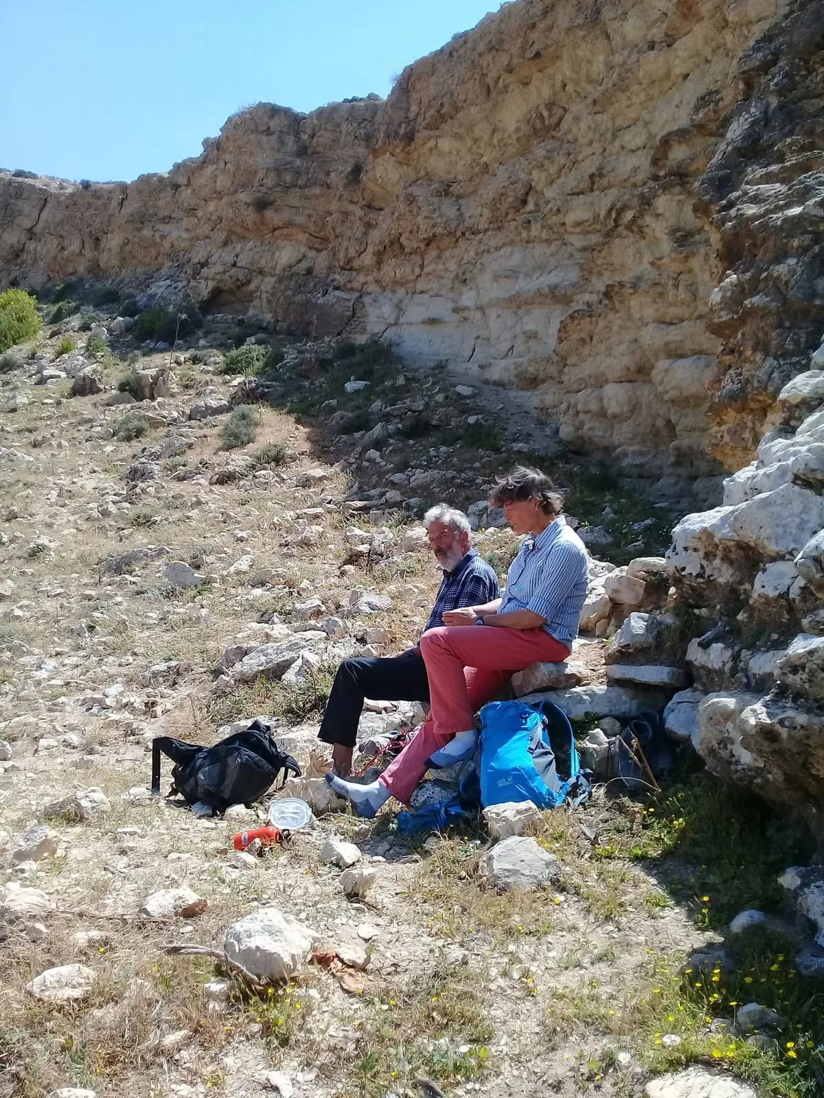 Halte à l’ombre de la falaise, sacs posés à terre