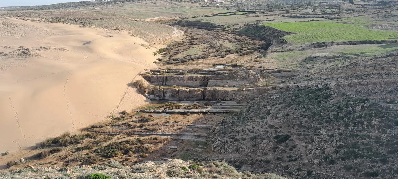 Le sable déborde sur les terrasses de roche