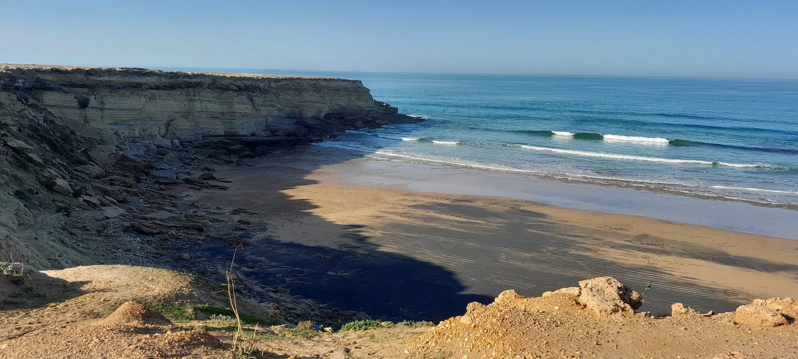 Dalle noire affleurant sur la plage à marée basse