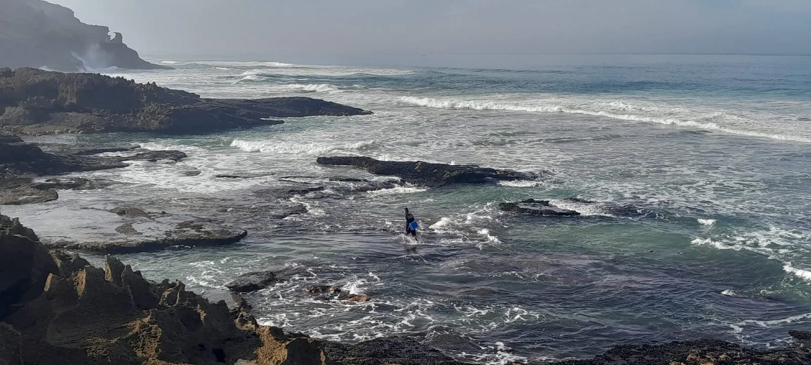 Le récif battu par les vagues, un pêcheur au bord